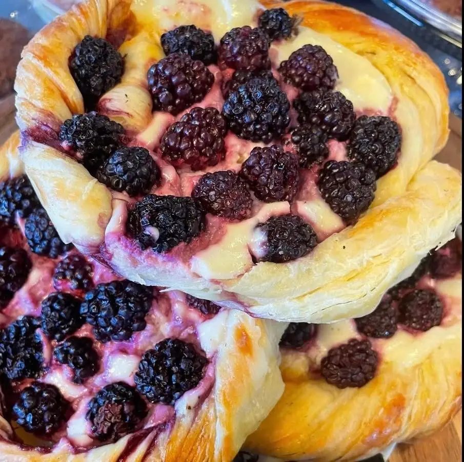 Blackberry and cream cheese danishes stacked on a board